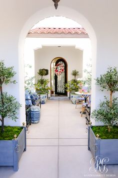 an archway leading into a room with potted plants and chairs on the side walk