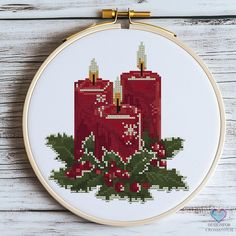 a cross stitch pattern with two red candles