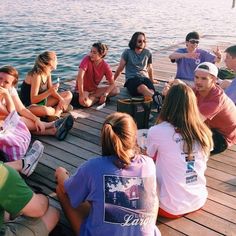 a group of people sitting on top of a wooden pier