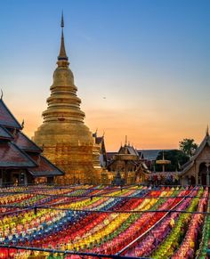 many colorful lanterns are lined up in front of a large building with a golden spire