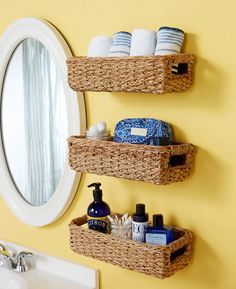 two wicker baskets are hanging on the wall above a sink in a yellow bathroom