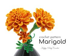 two orange flowers in a black vase with the words, crochet pattern margold