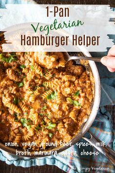 a person is holding a spoon over a bowl of hamburger helper with pasta in it