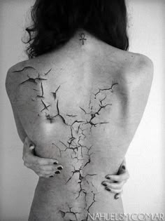 the back of a woman's body with cracked paint all over it and her hands on her hips