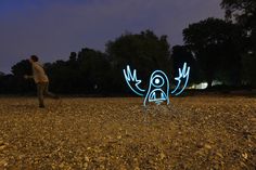 a man standing in the middle of a field next to a lit up bird figure