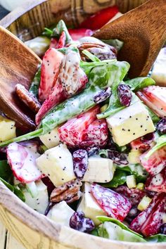 a salad in a wooden bowl with two wooden spoons on top of the salad