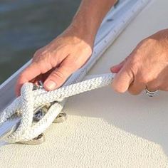 a person pulling a rope off the side of a boat with their hands on it