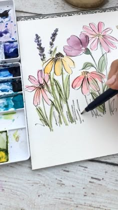 someone is painting flowers with watercolors on paper