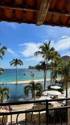 an outdoor swimming pool with palm trees and the ocean in the backgroung