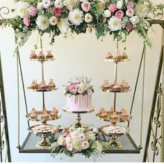 a table topped with a pink cake and lots of cupcakes