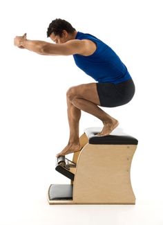 a man is doing squats on an exercise bench while holding his arm out to the side