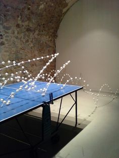 a ping pong table with white balls on it in front of a stone wall