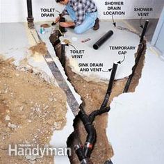 a man is working on the floor in his bathroom that has exposed pipes and plumbing