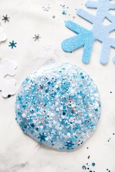 there are snowflakes on the table with blue and white confetti next to it