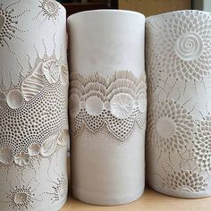 three white vases sitting on top of a table next to each other with intricate designs