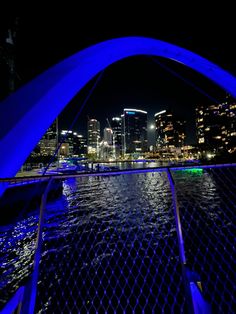 the city skyline is lit up at night as seen through an arched bridge over water