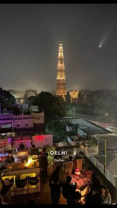 people sitting at tables in front of the eiffel tower lit up with lights