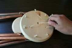 a person is making a clock out of wood and stringing it with white beads