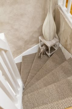 a white vase sitting on top of a stair case next to a wooden banister