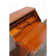 an old wooden desk with drawers on the bottom and one drawer open to show what's inside