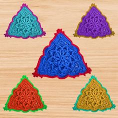 six crocheted triangulars are arranged on a wooden surface, each with different colors