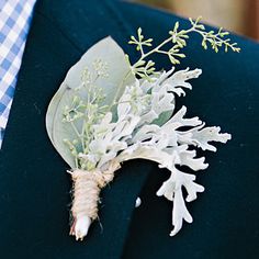 a boutonniere with white flowers and greenery on it's lapel