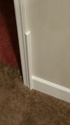 a white door is open in the corner of a room with carpet on the floor