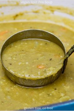 a ladle filled with soup sitting on top of a blue bowl full of soup