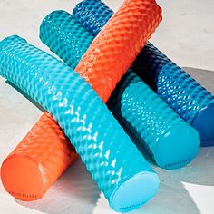 four blue and orange grips are laying on the ground, one has an orange top