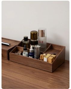 a wooden drawer with some bottles and other items in it on top of a table