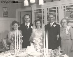 an old black and white photo of a bride and groom with their family at the dinner table