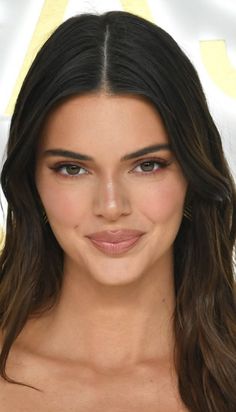 a woman with long hair and brown eyes wearing a strapless top smiles at the camera