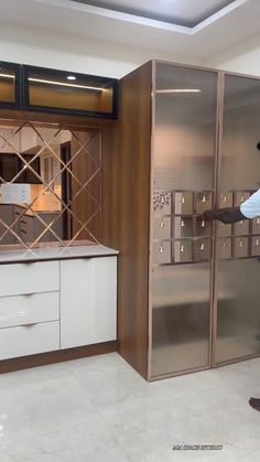 a man standing in front of a kitchen with white cabinets and glass doors on the wall