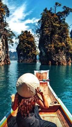 a woman in a hat is sitting on a boat looking out over the water at some small islands