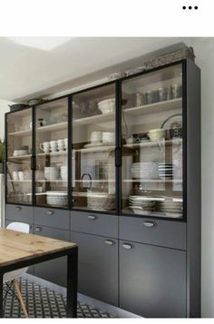 a dining room table and chairs in front of a china cabinet with many dishes on it