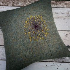 a green pillow with a yellow dandelion embroidered on it