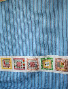 a blue and white striped wall hanging next to a bed covered in colorful sheets with pictures on them