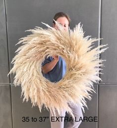 a woman standing in front of a wall holding a large furry thing up to her face