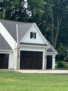 a white house with two brown garage doors