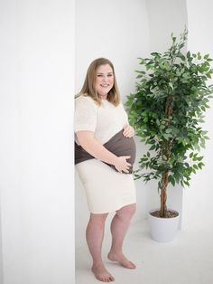 a pregnant woman standing next to a potted plant