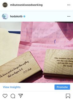 two wooden stamps with words on them sitting on top of pink paper and envelopes