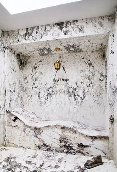 a bathroom with marble walls and flooring in the shower area is pictured here, it has a skylight above