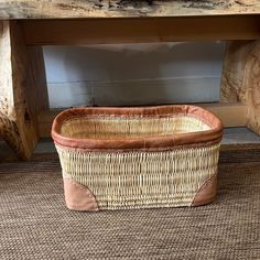 a wicker basket sitting on the floor under a wooden table with a bench in the background