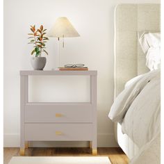 a white nightstand with a plant on it next to a bed and a night stand