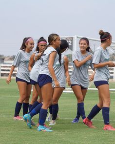 a group of young women standing next to each other on top of a soccer field