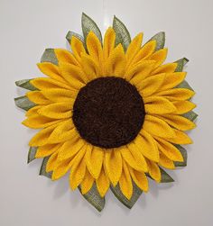 a large yellow sunflower is hanging on the wall