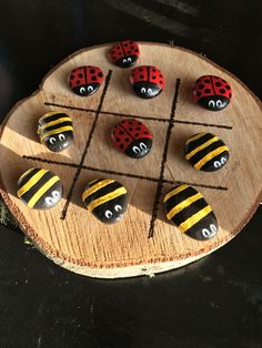 a wooden board topped with lots of rocks covered in painted ladybugs and bees