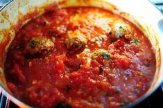 a pan filled with meatballs and sauce on top of a stove