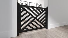 an open black gate in the corner of a room with hardwood floors and white walls