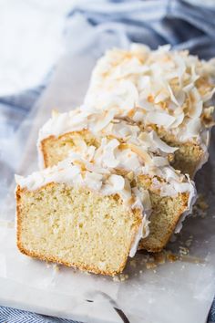 two slices of cake with white frosting and coconut toppings on top, sitting on a piece of parchment paper